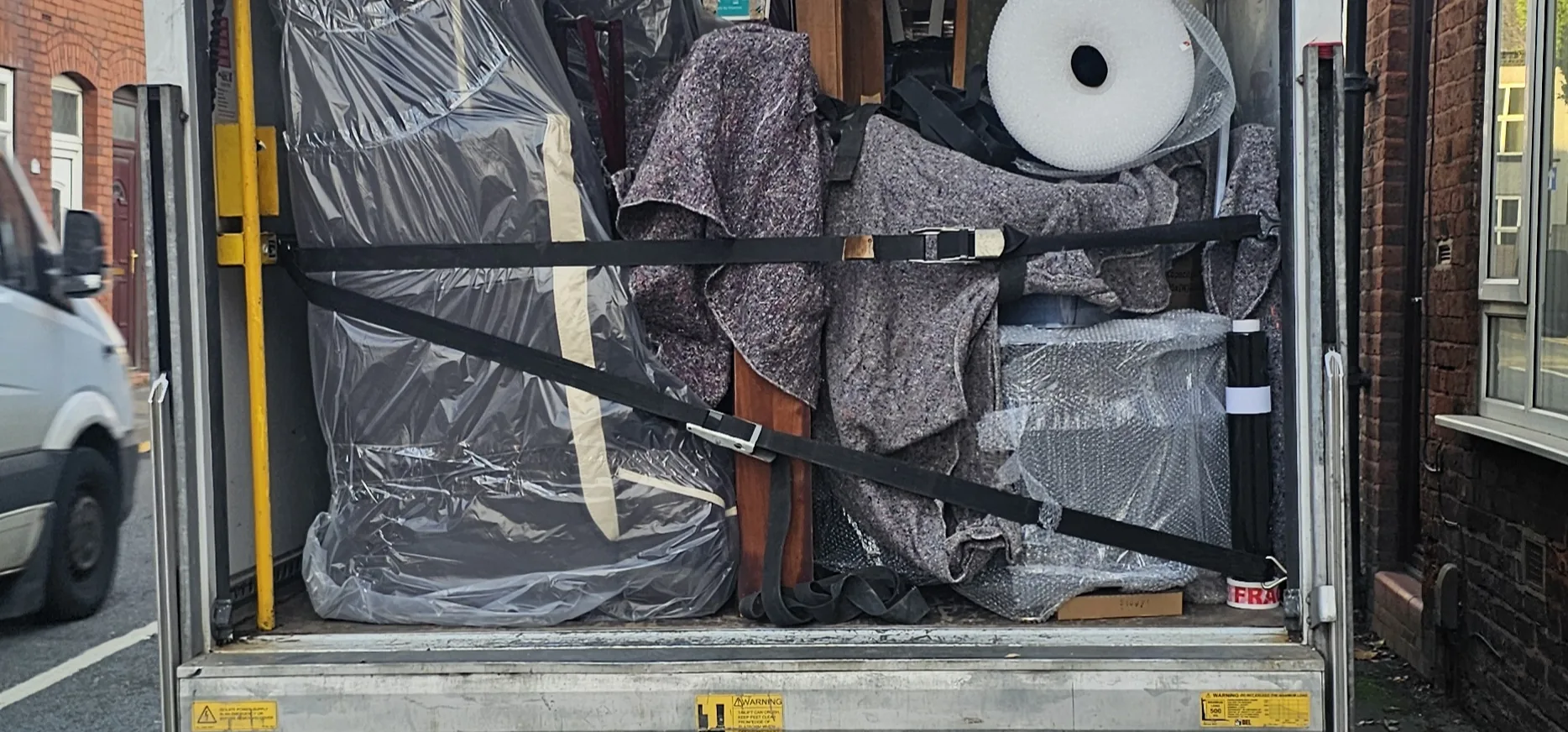 Wrapped and strapped furniture in the back of a ReloCore UK van on a terraced street